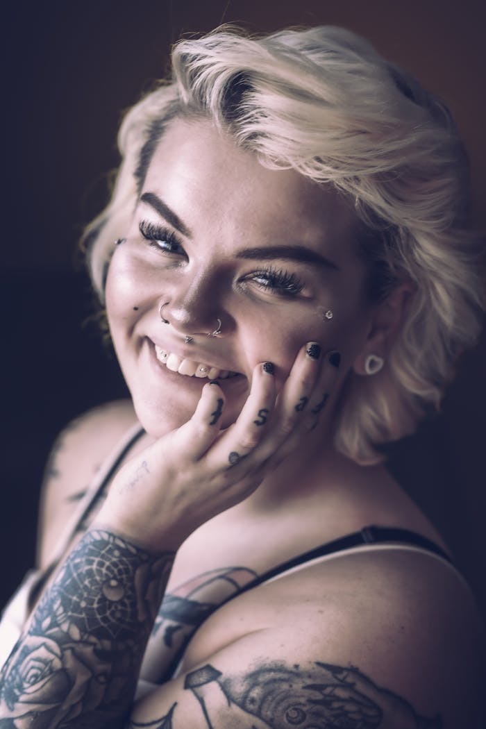 Home Close-up portrait of a blonde woman with tattoos and a bright smile.