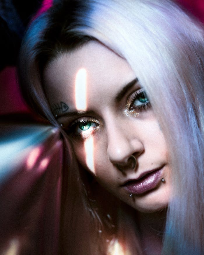 Home Artistic close-up of a woman with piercings and green eyes, featuring a dramatic light effect.